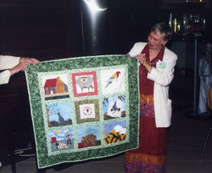 Nan Duncan, E.D., presenting quilted wall hanging to host club in Adelaide